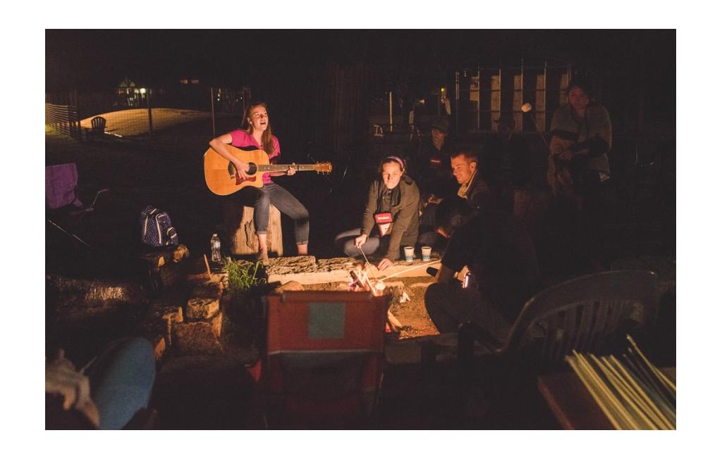 Summit attendees sitting around a campfire for a sing-along