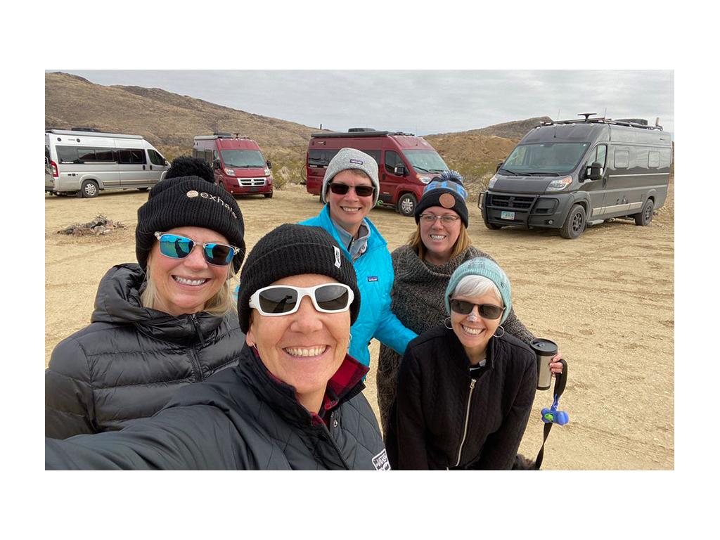 Travato friends huddled together for a picture with Travatos in background