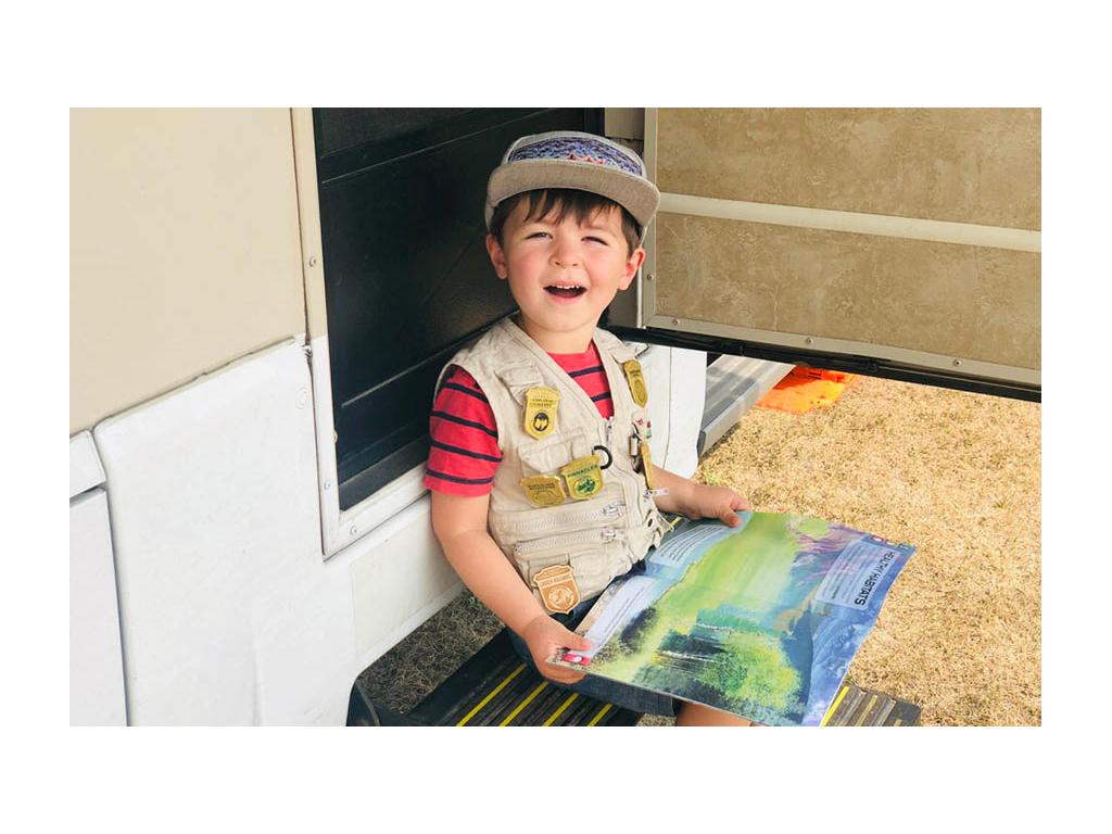 Caspian sitting on View steps reading junior ranger book