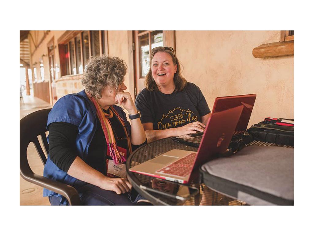 Two RVE attendees sitting at table with laptops in coworking space
