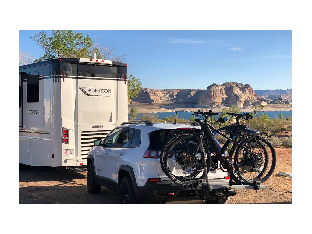 Winnebago Horizon with white tow car parked near blue water