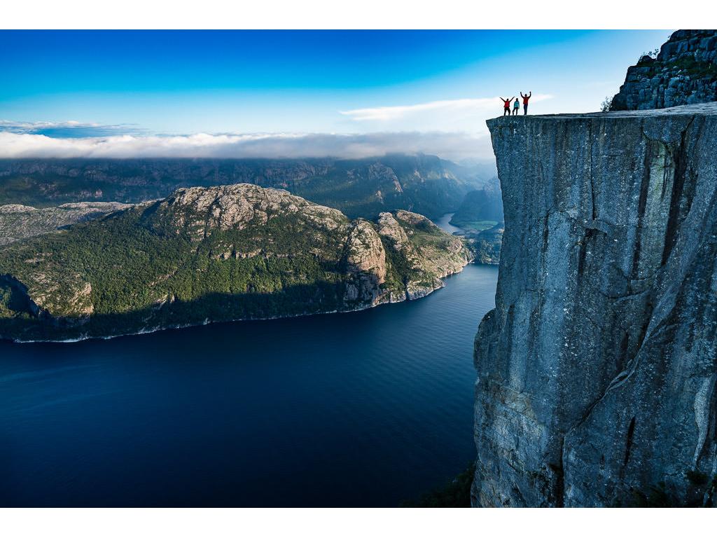 The Holcombes standing at the edge of Pulpit Rock looking over a landscape of water and mountains