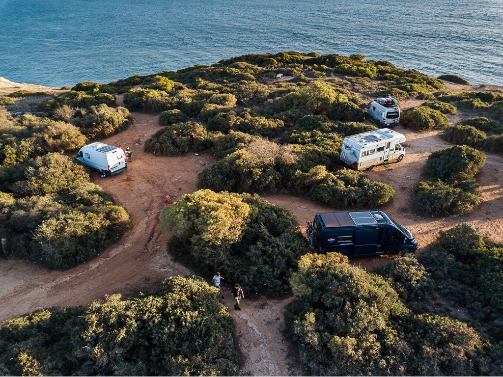 Winnebago Revel parked with 3 other motorhomes next to a body of water