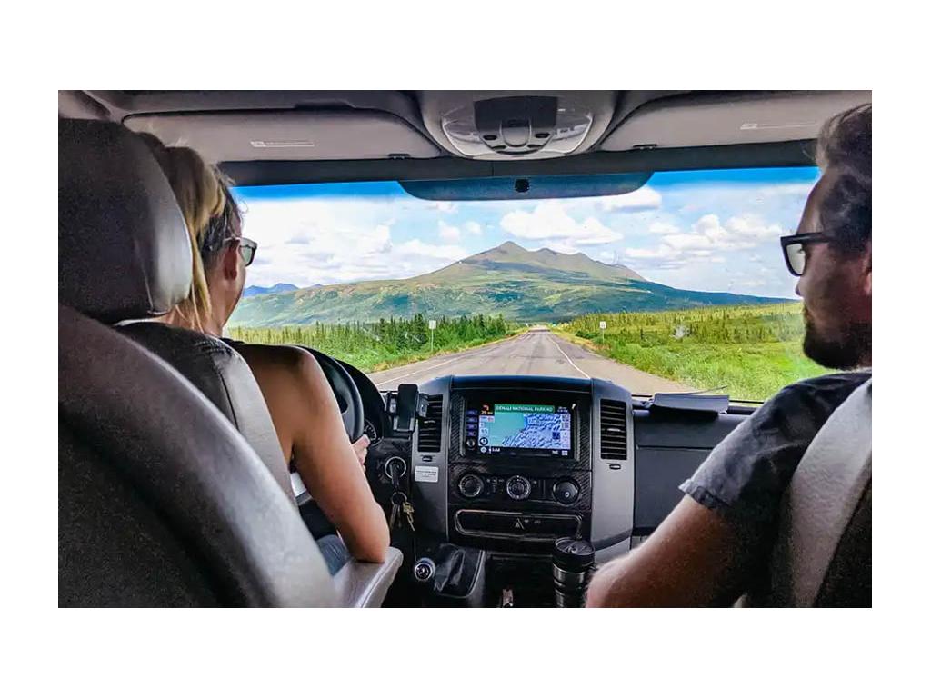 Two hands on steering wheel driving through mountains