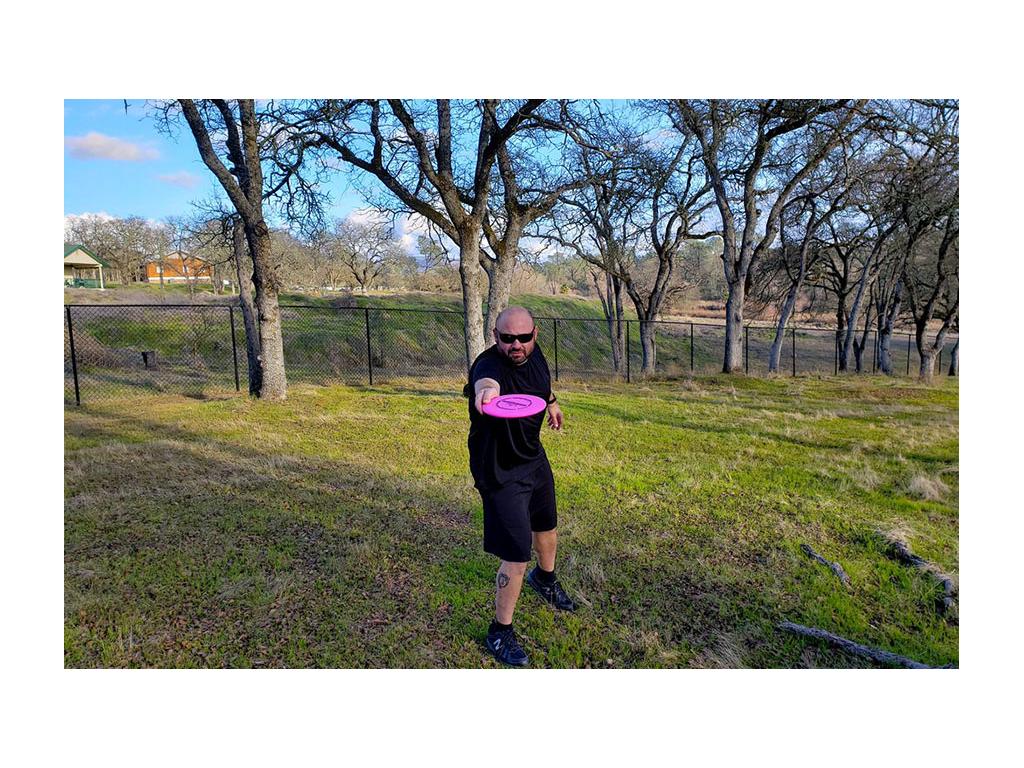 Kenny throwing pink Frisbee in grass