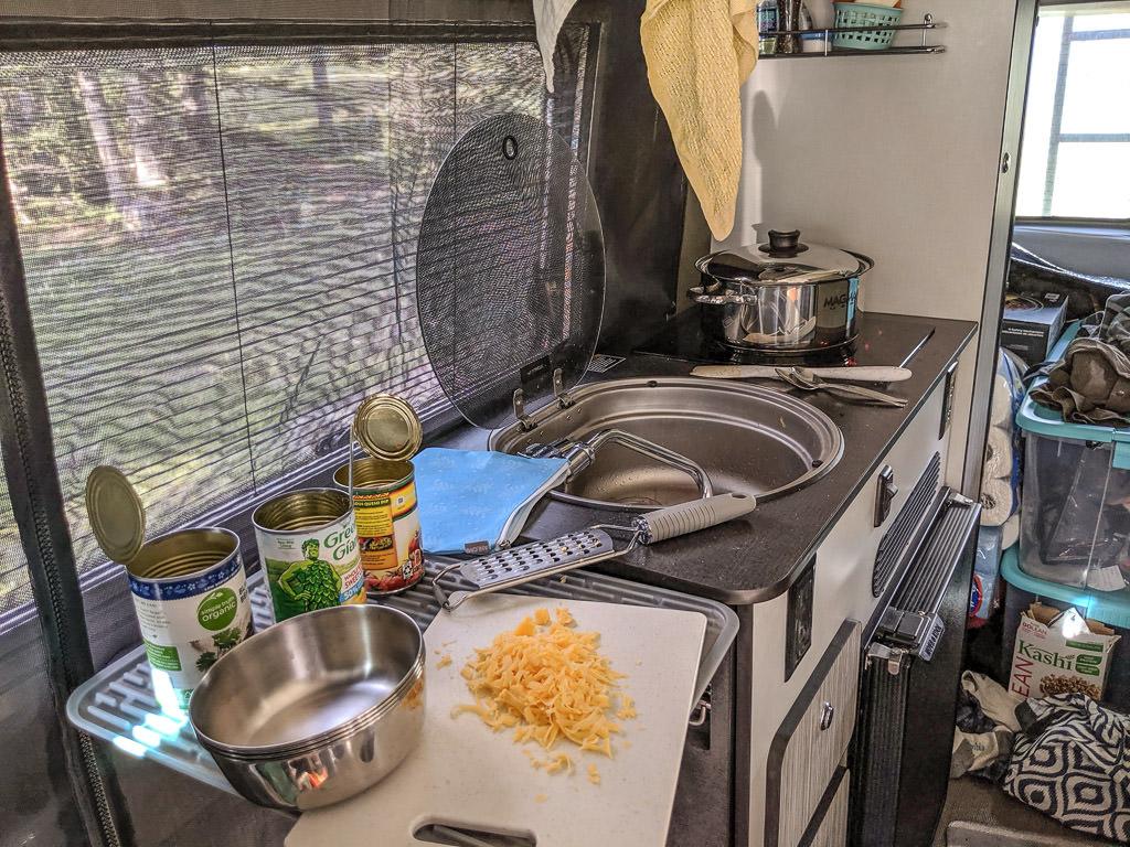 Opened cans of vegetables and grated cheese on kitchen counter