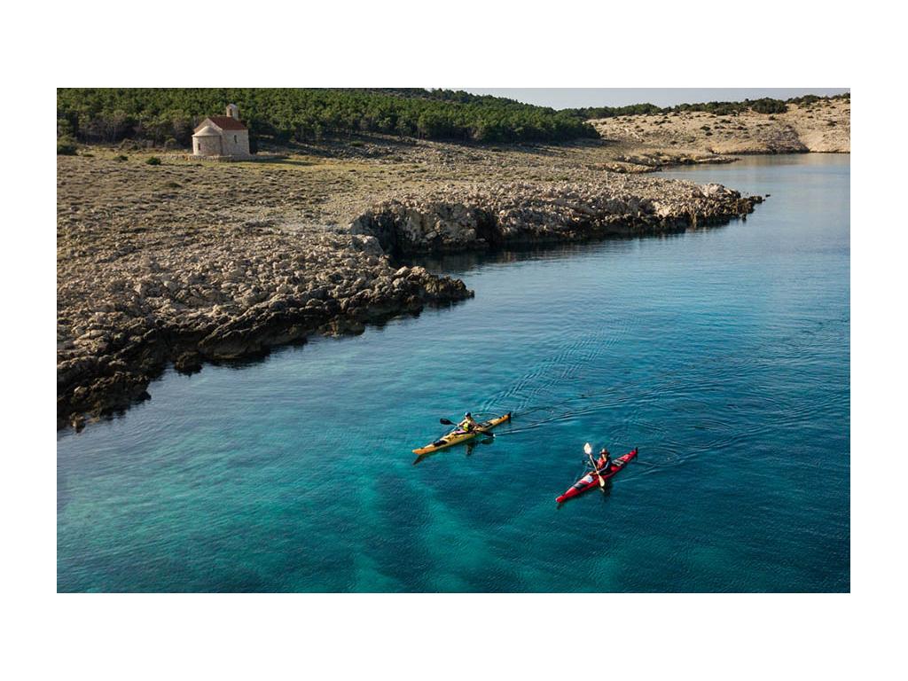 Border separating windward and leeward side of the Isle of Rab with Abby and Kathy on kayaks in water