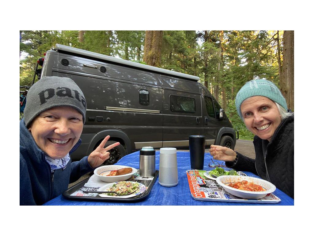 Noel and Chris eating at picnic table outside of Travato