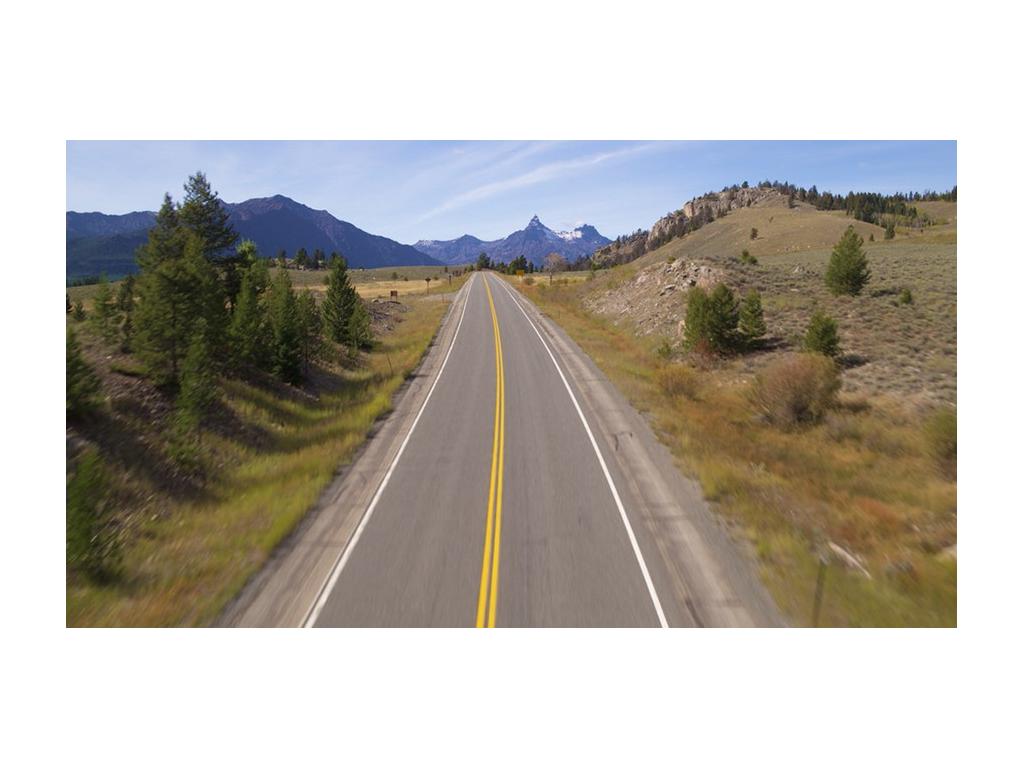 A long, open road with mountains in the distance