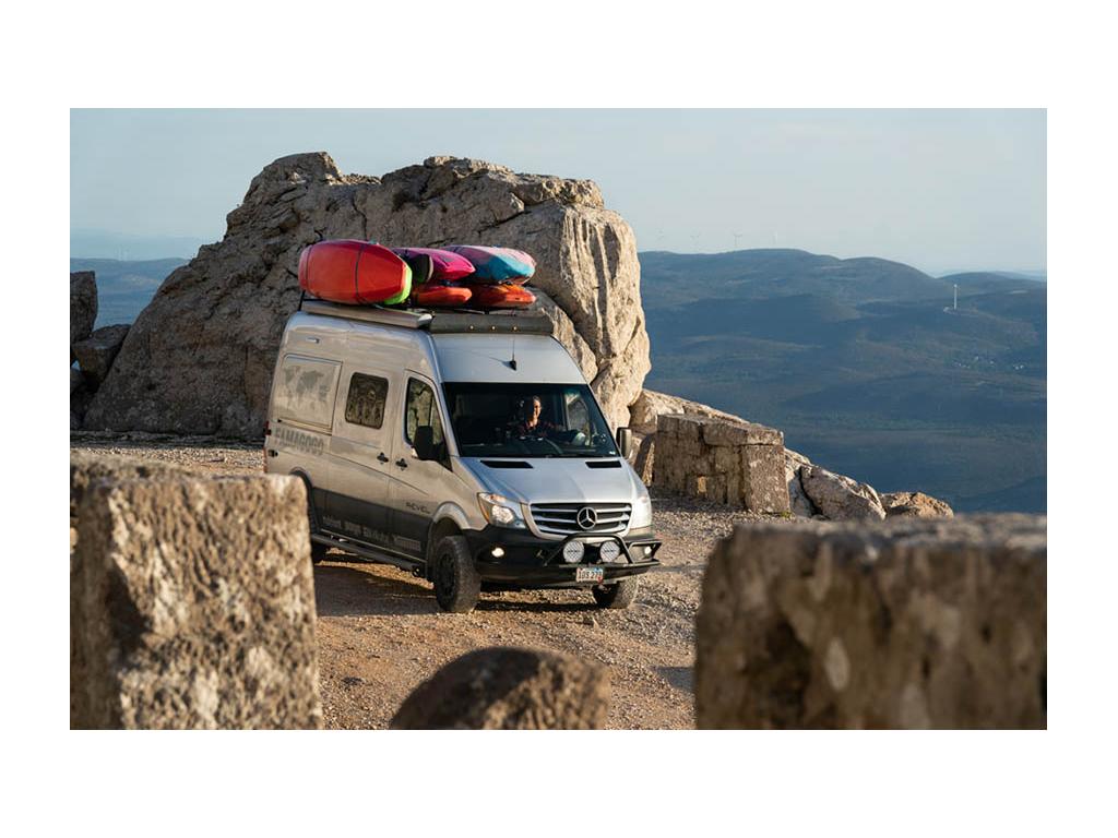 Kathy driving Revel with kayaks on top