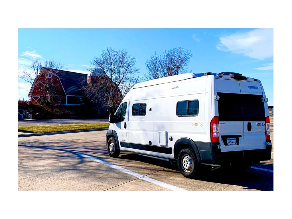 Winnebago Solis parked in parking lot across the street from a red barn