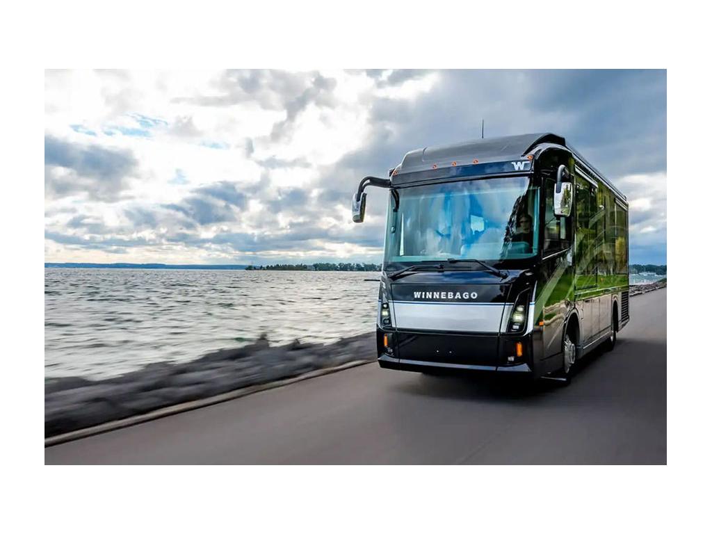 Winnebago Journey driving down road near water.