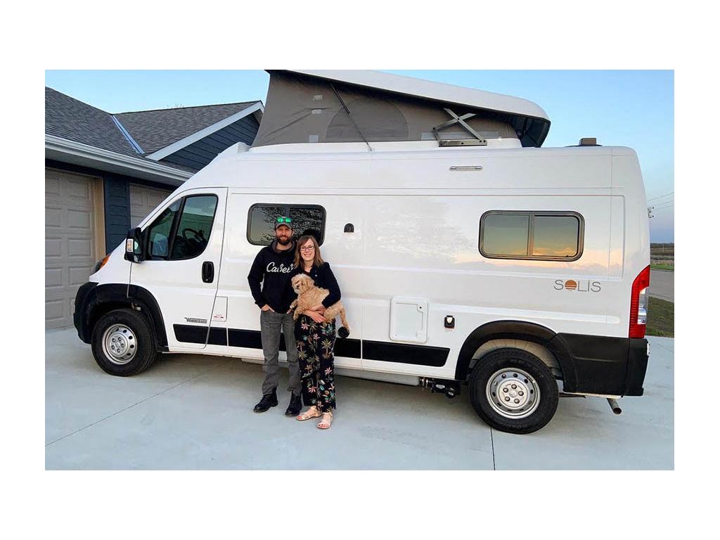 Lindsey and Dan holding their pup in front of Solis