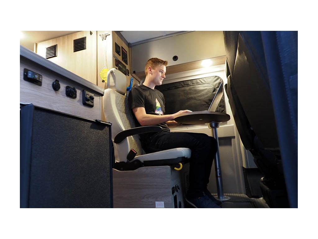 Mikah sitting at dinette seat doing work on laptop