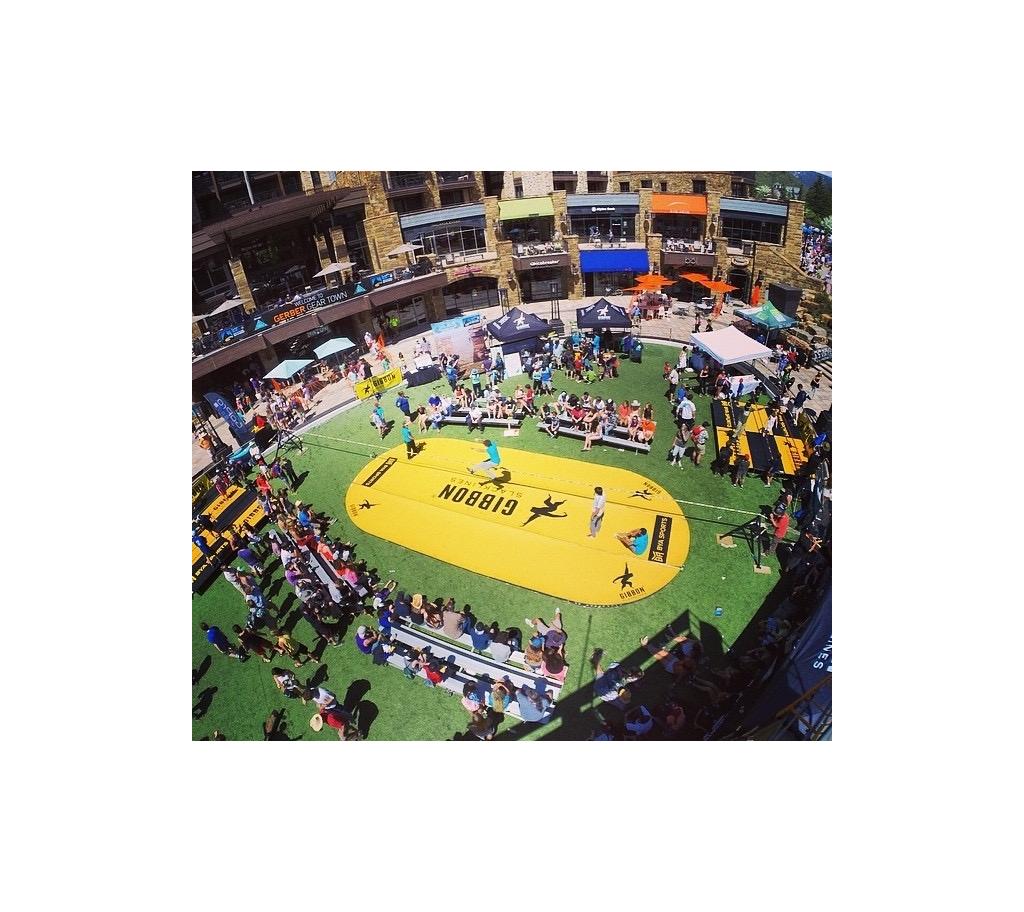 Crowd gathered around person going across a slackline.