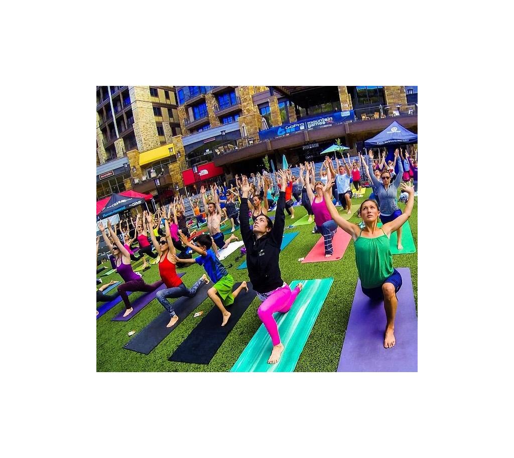 Large group of people doing yoga in the grass.