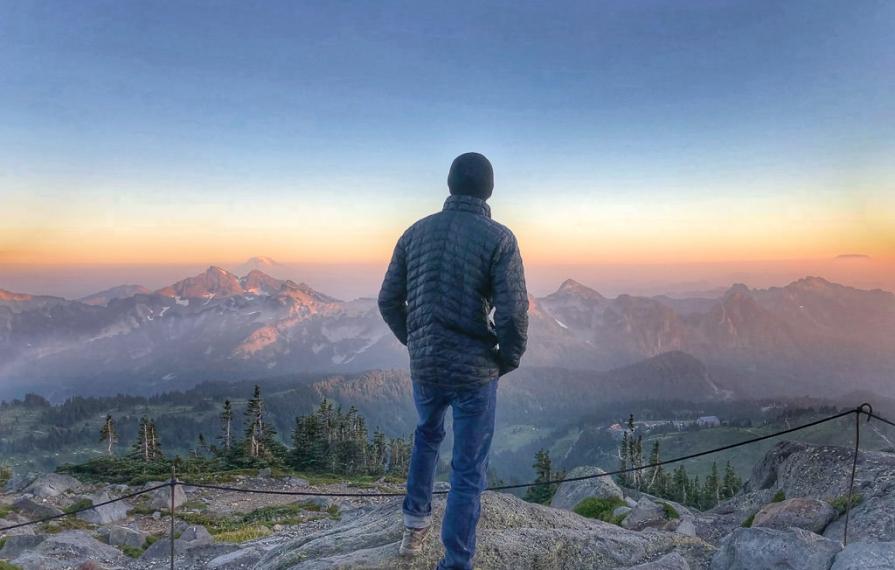 Man looking out over the mountains from a lookout.
