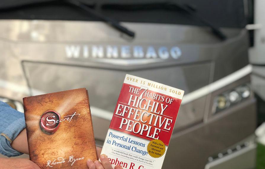 Handing holding 2 paperback books in front of Forza