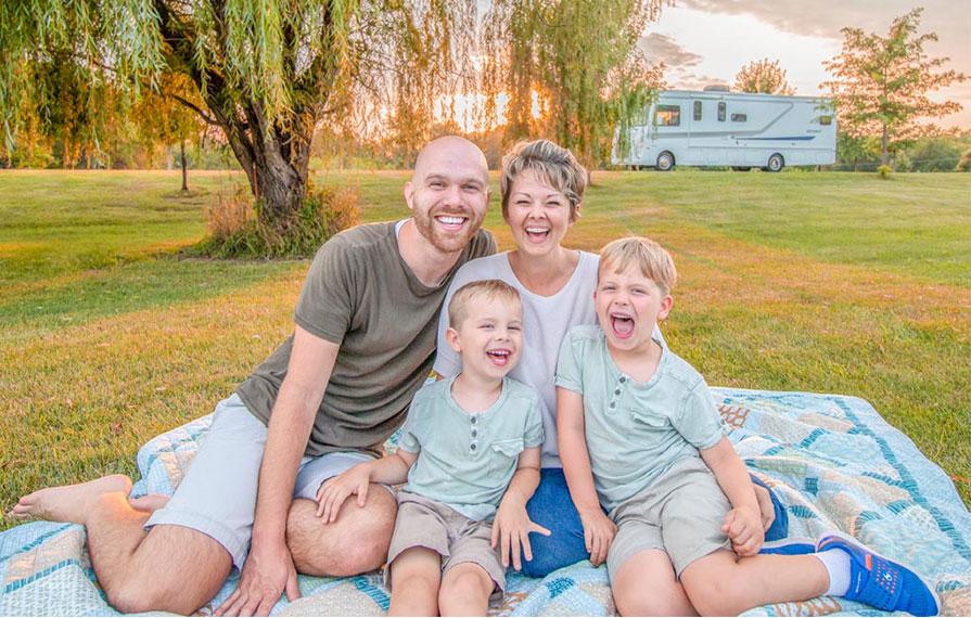 Farish family sitting smiling with beautiful trees and Winnebago Intent in the background