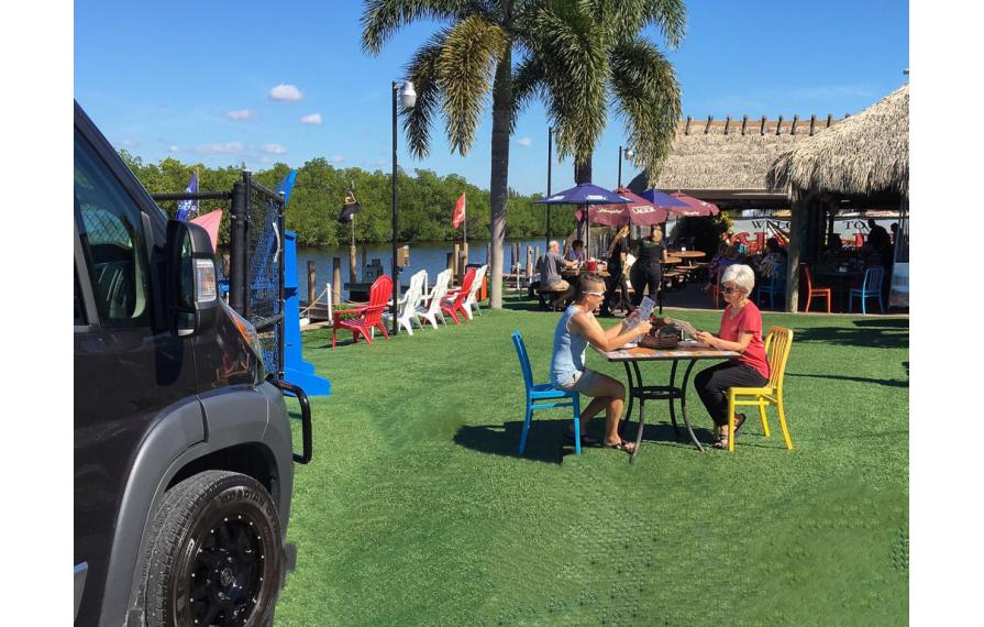 Chris and Noel sitting outside at a restaurant reading the menu. The Travato is near them.