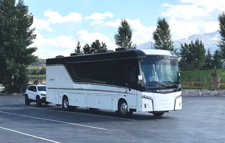 Winnebago Horizon with tow car in parking lot