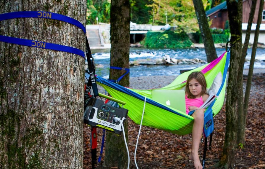 Abby sitting in green hammock doing homework on laptop