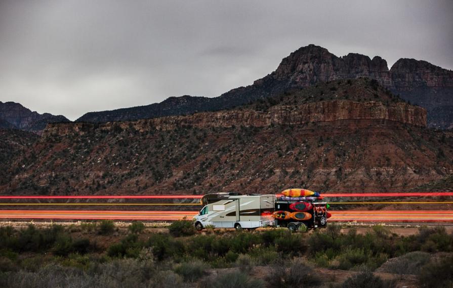 View driving in front of mountains pulling trailer with many kayaks