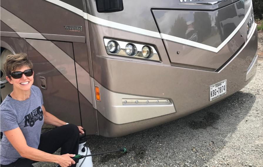 Woman sprays bug spray around campsite and motorhome to repel bugs