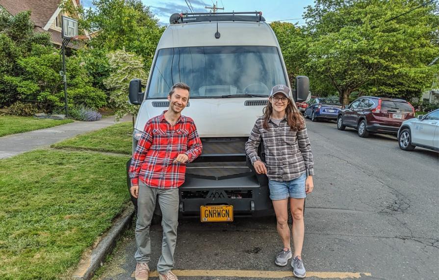 Young couple poses in front of their Winnebago Revel