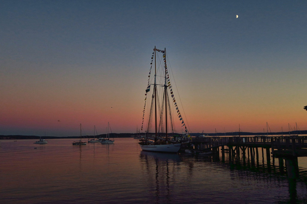 Boats on the water and one docked at sunset.