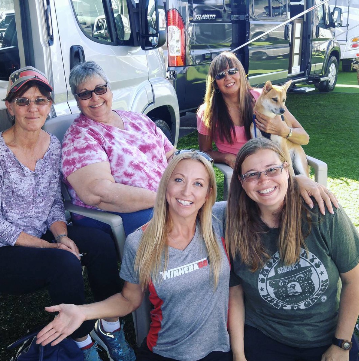 Group of women sitting outside motorhomes.