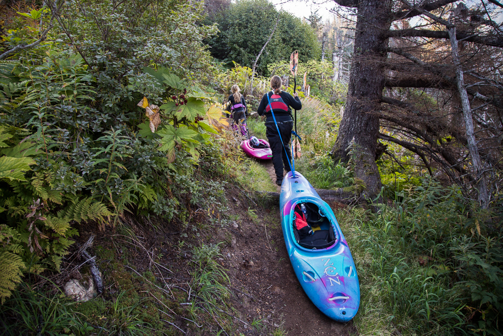 Two women pulling their rafts up a trail.