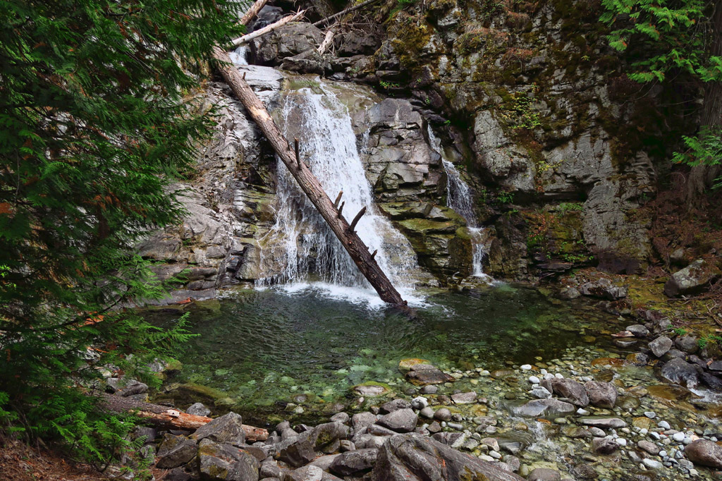 Small waterfall pouring over rocks into a pool of water below.