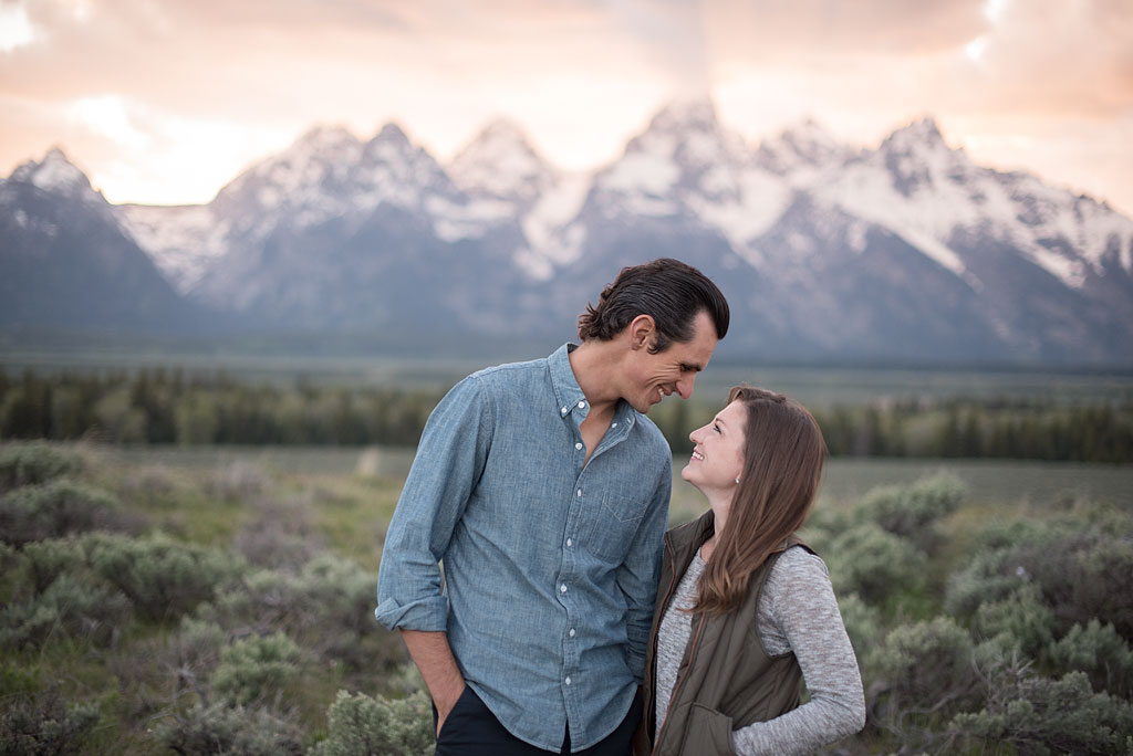 Jordan and Brittany smiling at eachother with mountains in the background.
