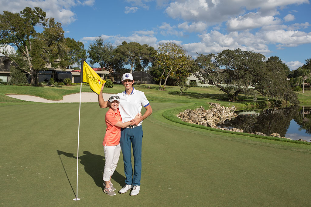 Jordan and Brittany standing next to the hole on a golfcourse.