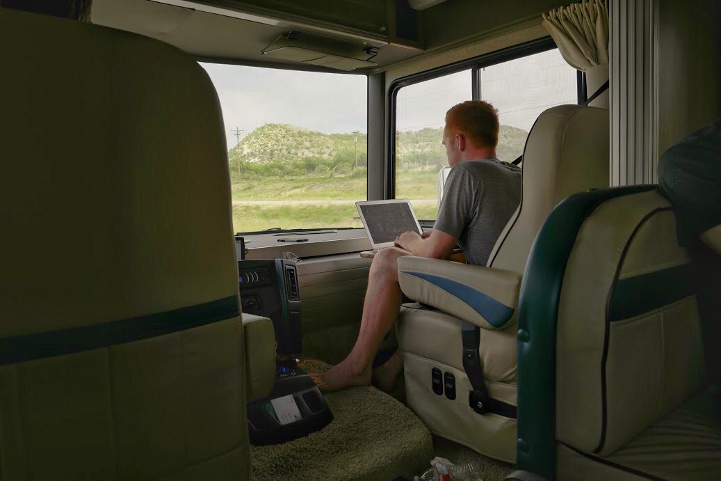 Heath working on laptop in passenger seat of motorhome.