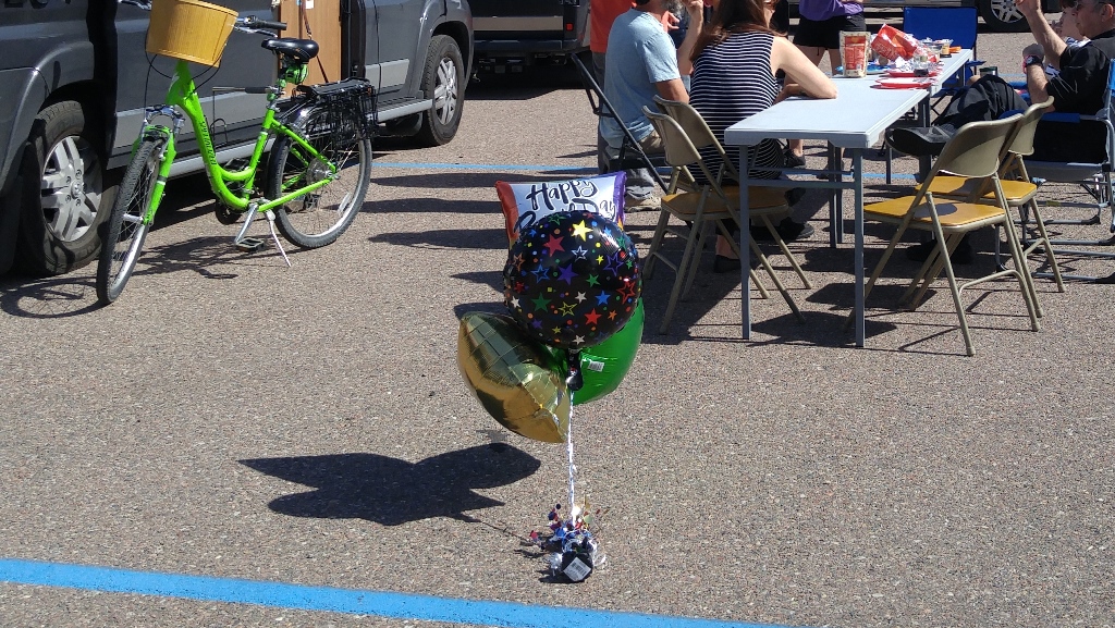 Birthday balloons and people sitting talking at a table.