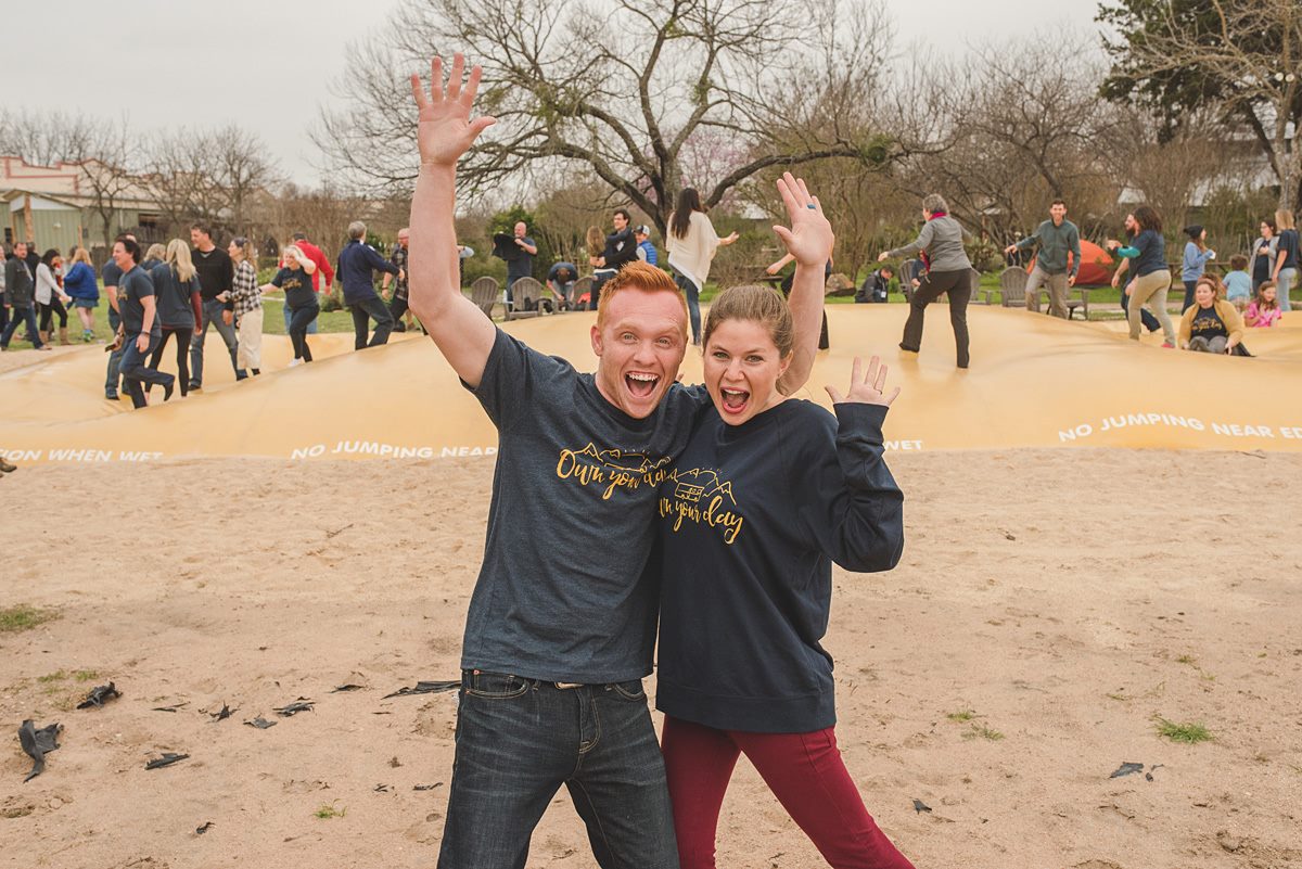 Heath and Alyssa Padgett with people behind them bouncing on a large bouncing bag.