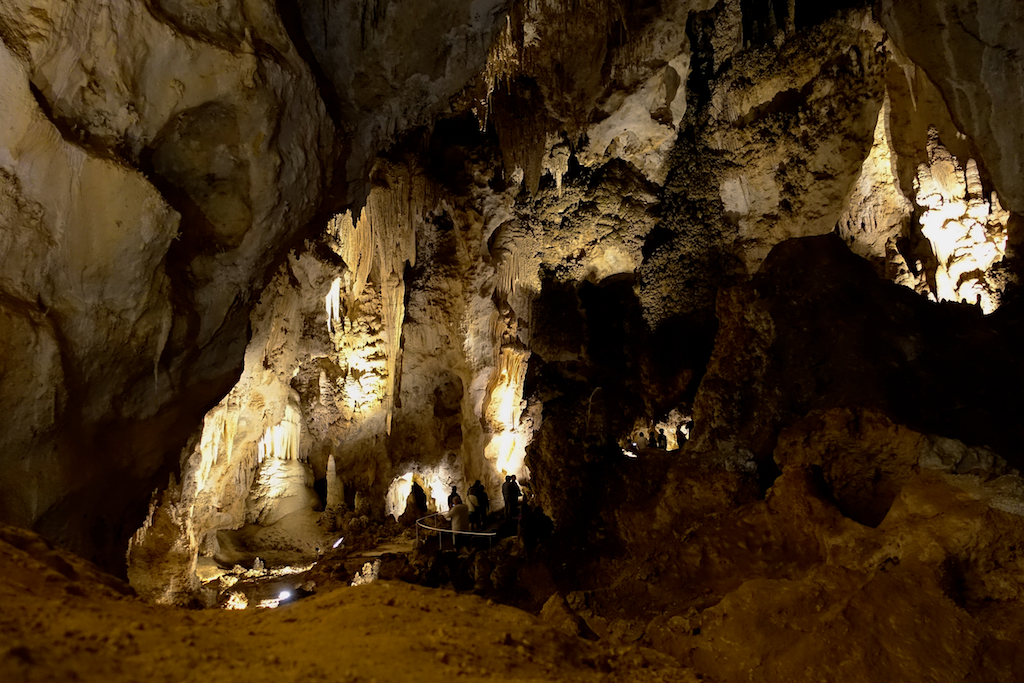 Incredible formations of stalagmites and stalactites within the cavern lit up by lights.