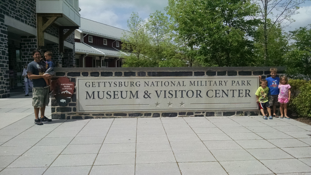 Man and four kids by Gettysburg National Military Park Museum & Visitor Center sign.