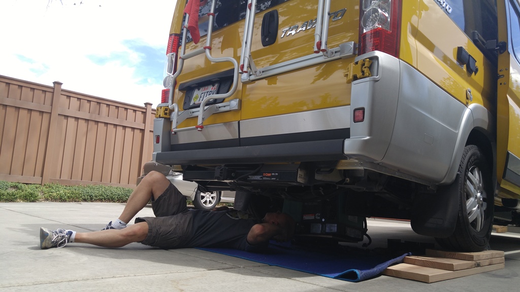 James laying underneath Winnebago Travato at the back of the unit.