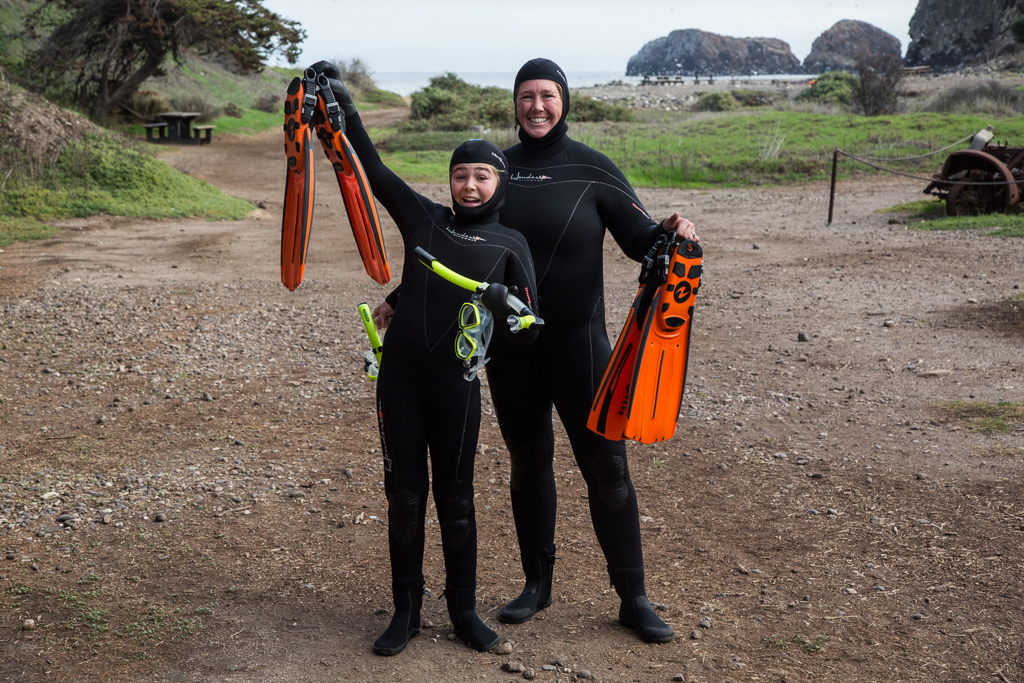 Kathy and Abby holding up their flippers on dry land.