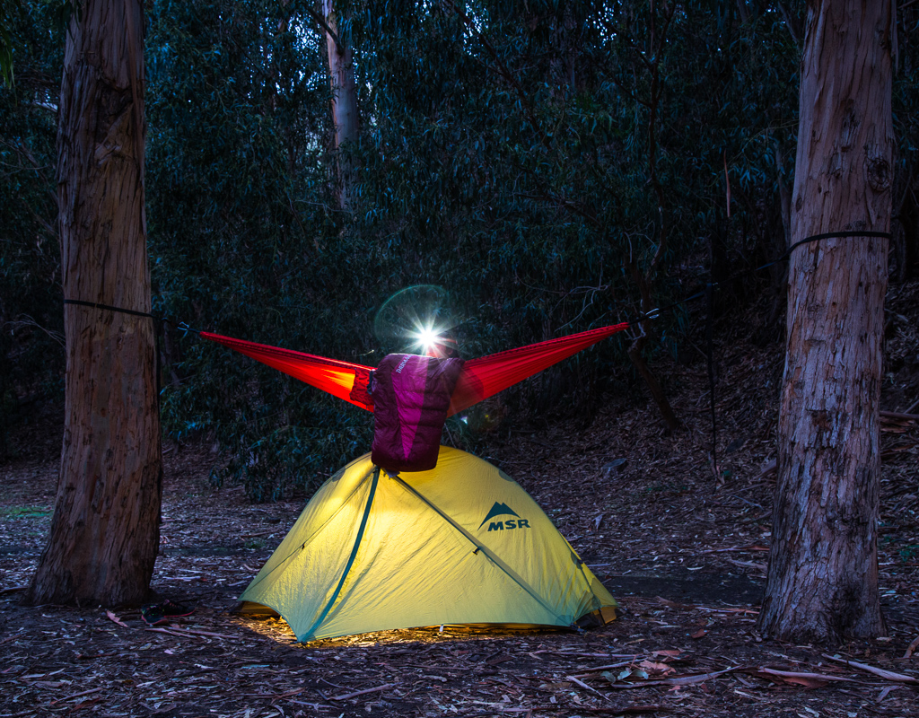 Abby in a hammock that is sitting above her tent.