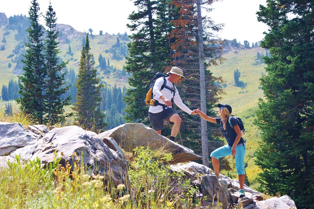 James helping Stef over rocks as they hike up a hillside.