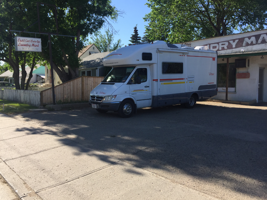 Winnebago View parked in the shade outside of a Laundry mart.