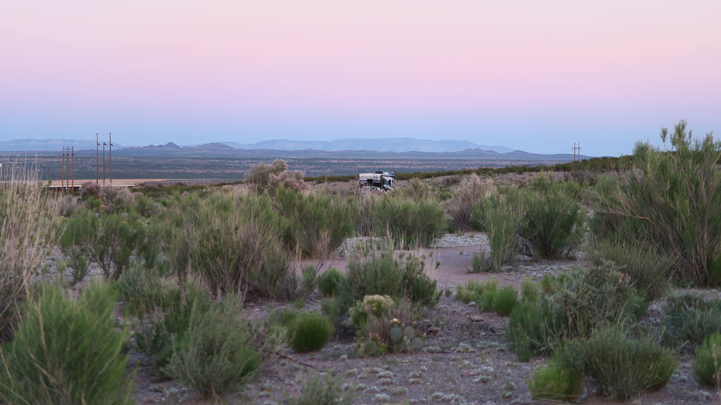 Winnebago View parked alone in a site in the desert with mountains in the background and a peaceful sunset.