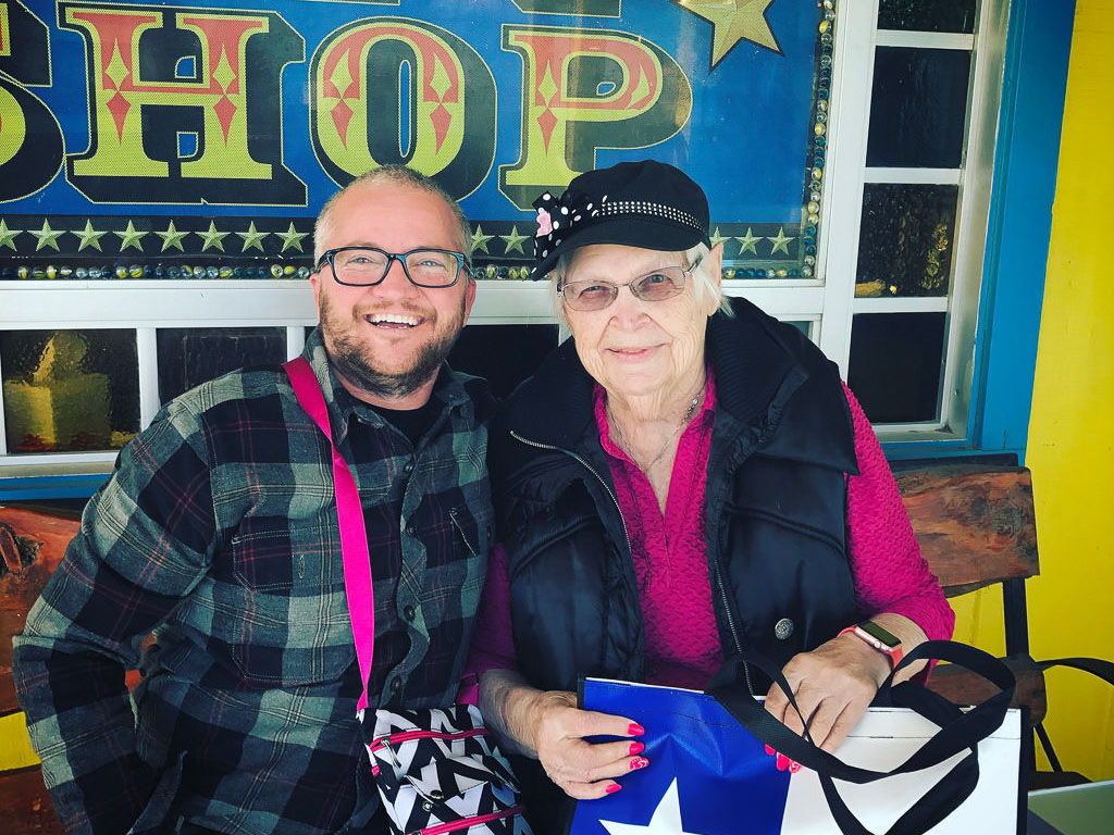 Two people sitting on a bench outside a shop.