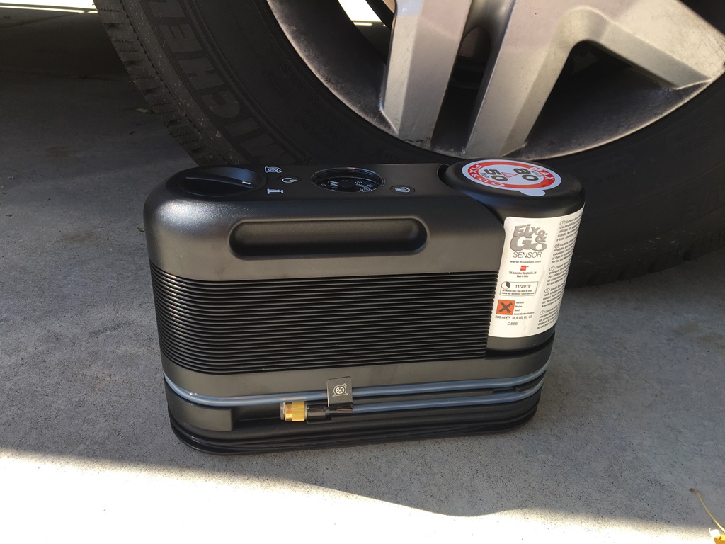 Air compressor sitting on the ground by tire.