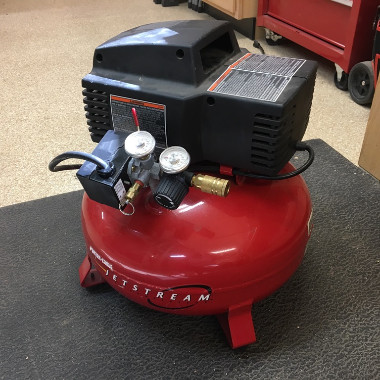 Pancake air compressor sitting on the floor.
