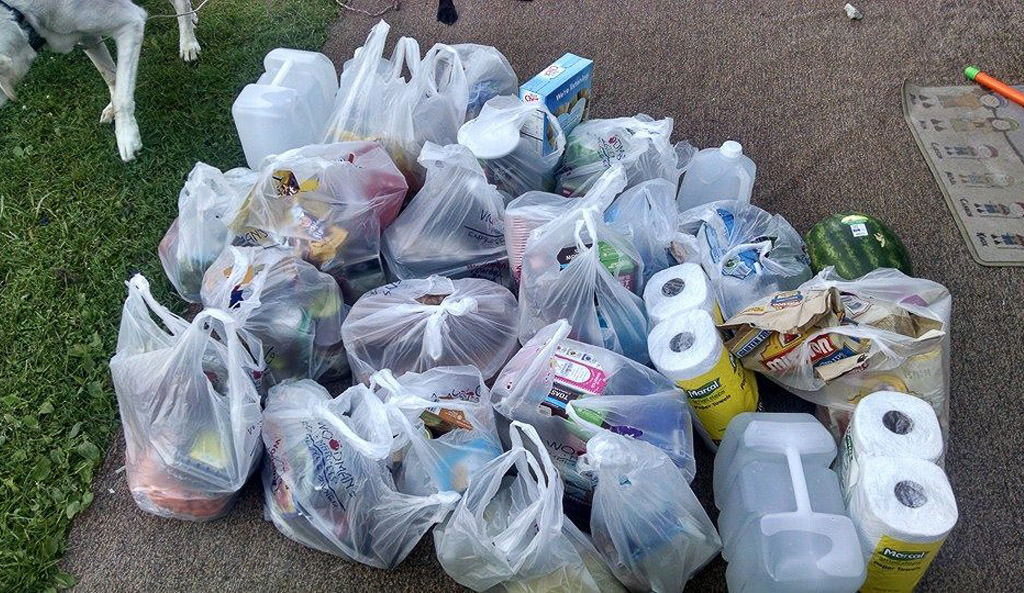 Bags full of groceries sitting on the ground.